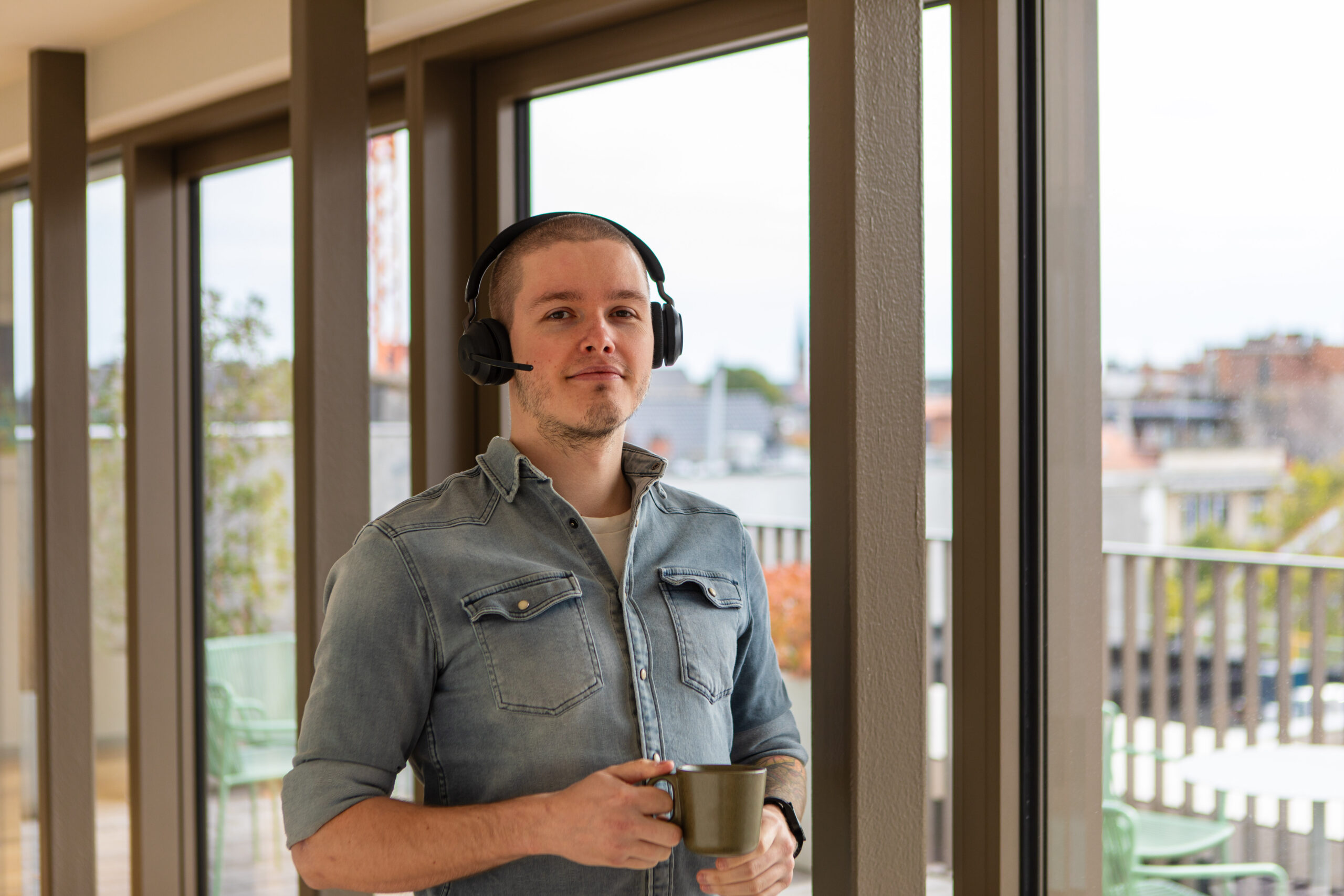 Medewerker Ascoo met tas koffie in de hand en headset op het hoofd.