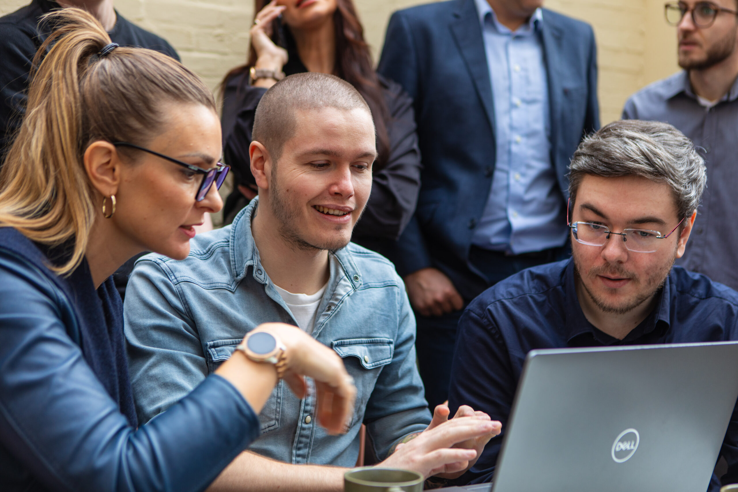 drie medewerkers verzamelen rond laptop en werken gefascineerd.