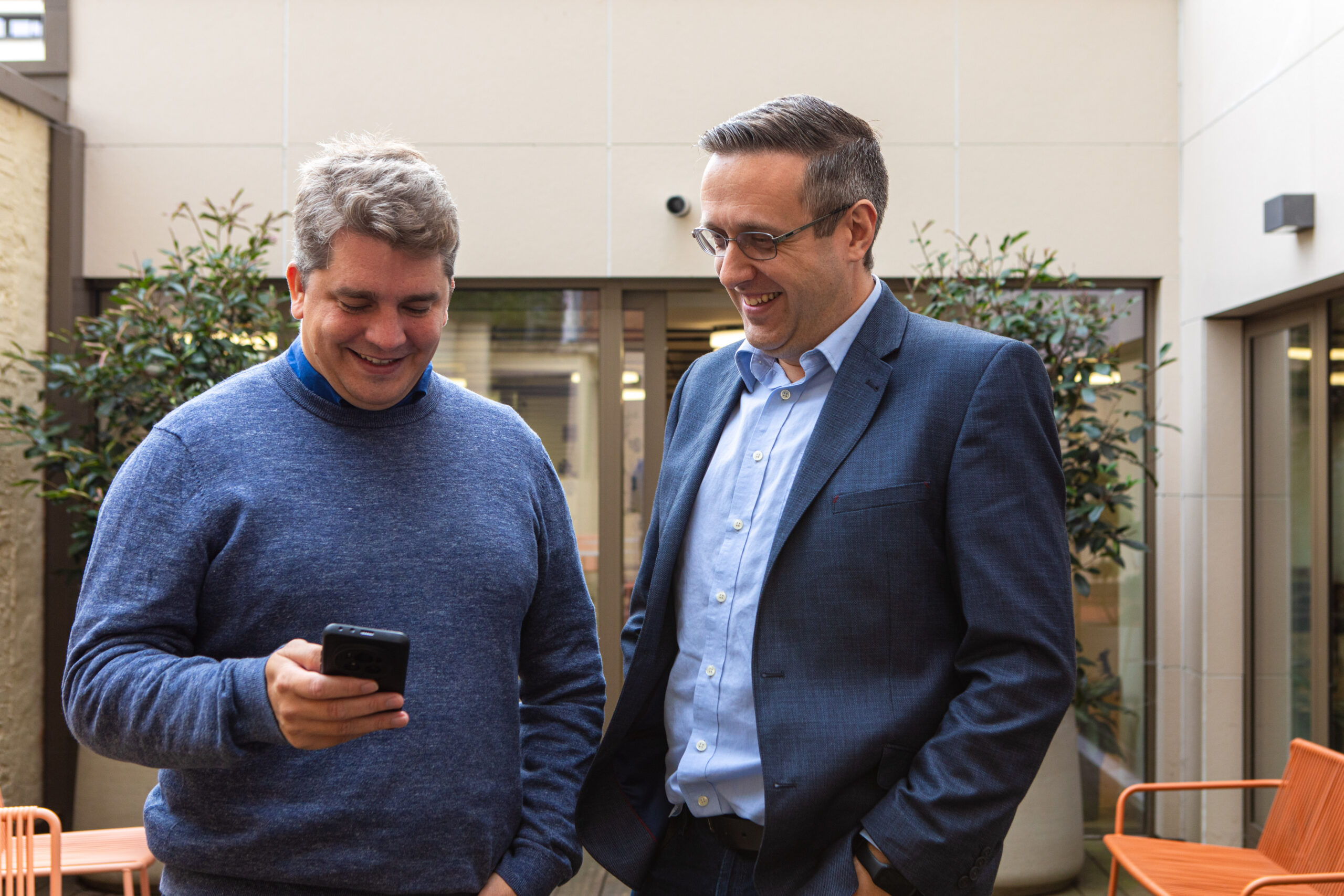 collega's Ascoo lachen samen naar het scherm van een smartphone.